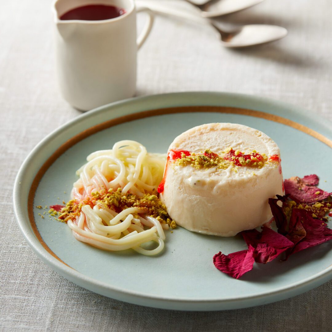 Elegant dessert with creamy mousse, fruit garnish, and a side of sauce.
