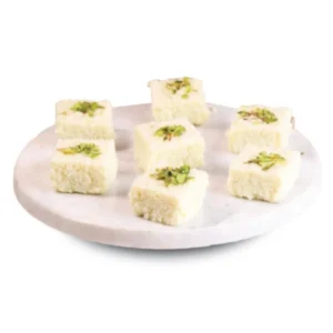 Plate of white square sweets garnished with pistachios.