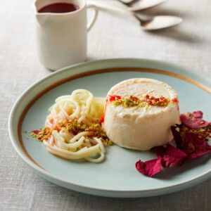 Elegant plated dessert with creamy mousse, fruit garnish, and sauce.