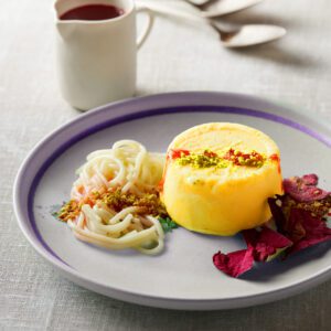 Elegant plated dessert with creamy mousse, fruit, and sauce.
